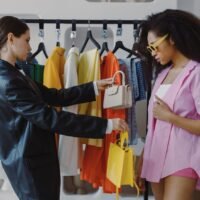 Two women shopping and exploring trendy fashion in a boutique setting.